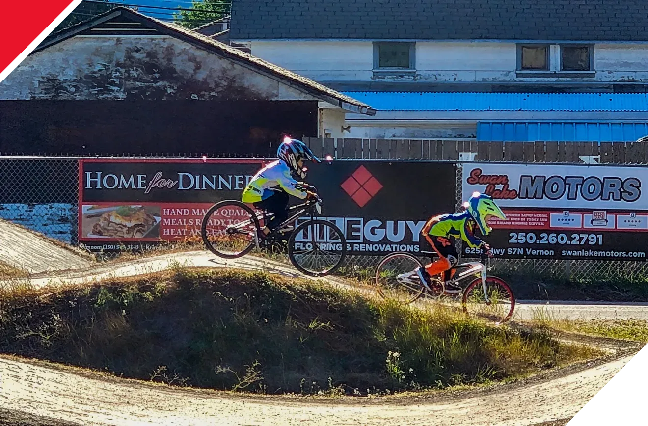 Kids riding mountain bikes in front of The Tile Guy sign