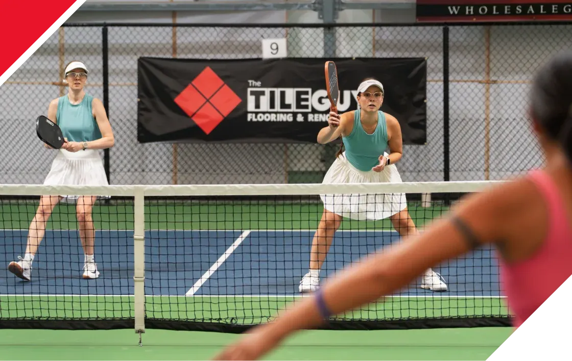 Pickleball players with a Tile Guy banner in the background
